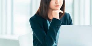 窓際でほほ笑むパソコンを見ている女性社員